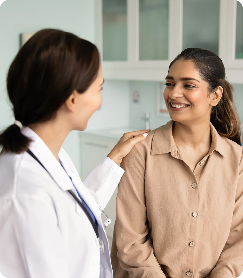 Dermatologist in white coat with stethoscope consulting with a patient in a clinical exam room